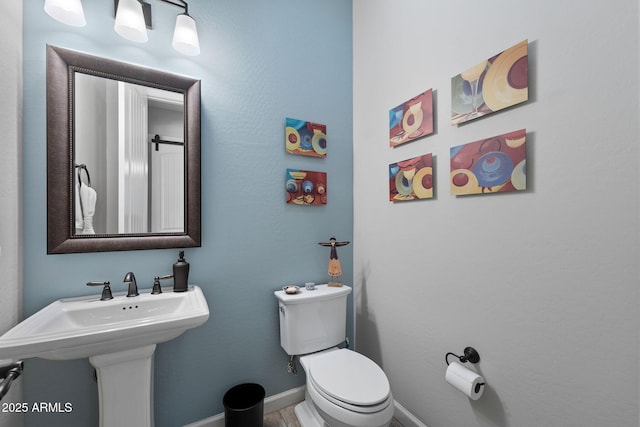 bathroom featuring baseboards, a sink, and toilet