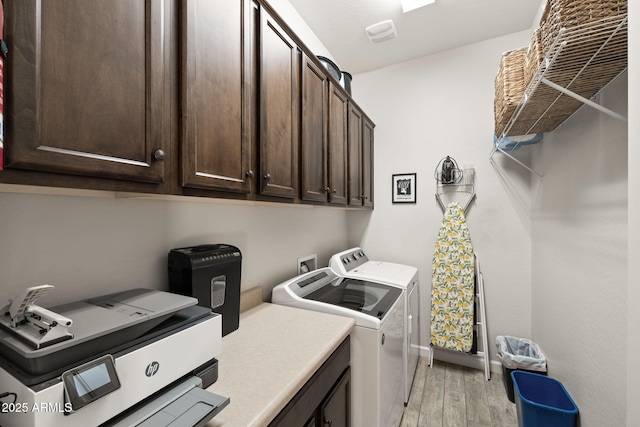 washroom featuring cabinet space, light wood-style flooring, baseboards, and washer and clothes dryer