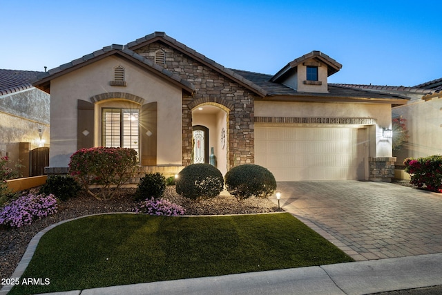 view of front of house with decorative driveway, stucco siding, a garage, stone siding, and a tiled roof