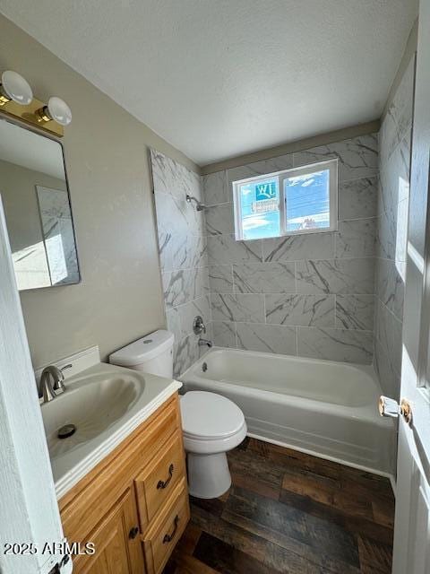 full bathroom with hardwood / wood-style floors, vanity, tiled shower / bath combo, and toilet