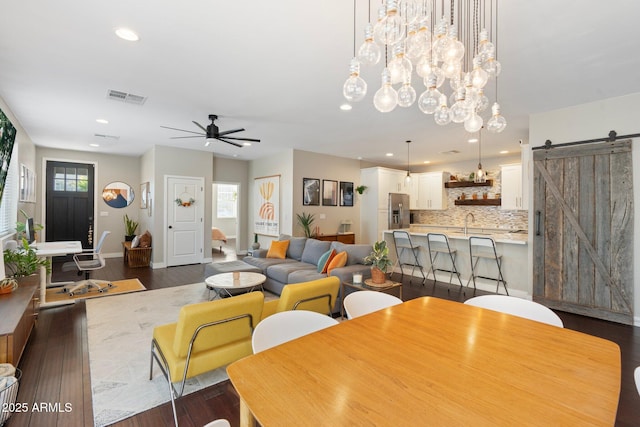 dining space featuring a barn door, visible vents, a ceiling fan, dark wood-type flooring, and recessed lighting