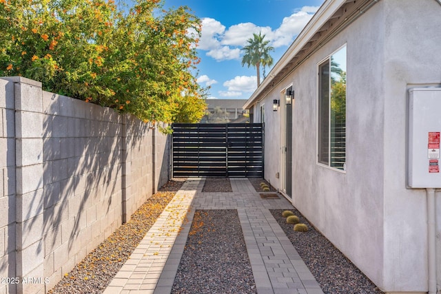 view of property exterior featuring a gate, fence, and stucco siding