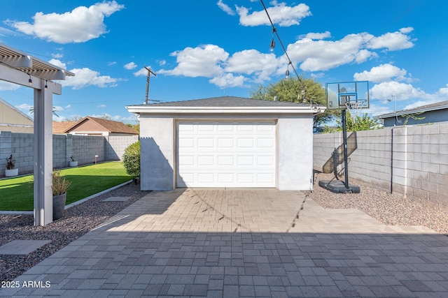 detached garage featuring decorative driveway and fence