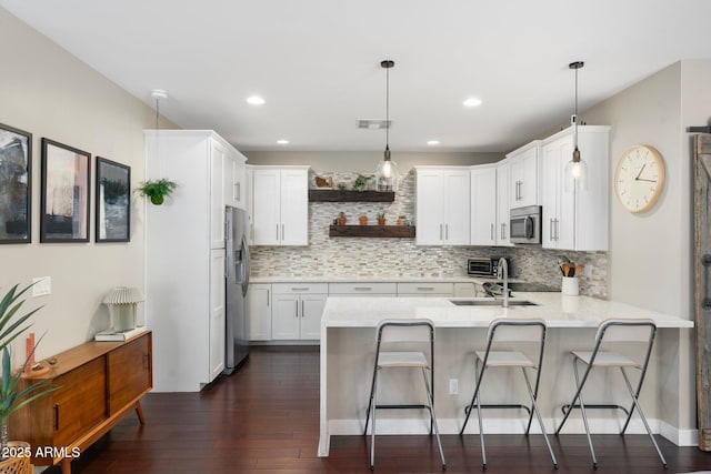 kitchen with white cabinets, appliances with stainless steel finishes, hanging light fixtures, a peninsula, and open shelves