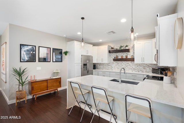 kitchen with a peninsula, stainless steel appliances, white cabinets, open shelves, and decorative light fixtures