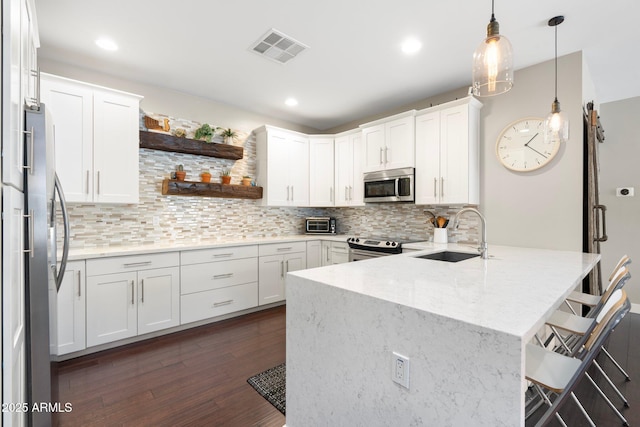 kitchen featuring a kitchen breakfast bar, stainless steel appliances, white cabinetry, open shelves, and a sink