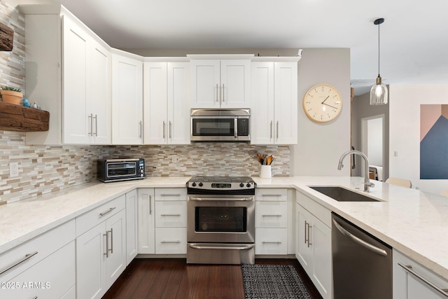 kitchen with stainless steel appliances, pendant lighting, white cabinets, and a sink