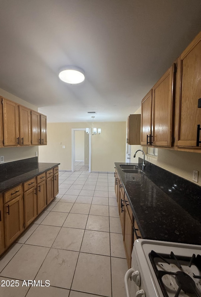 4913 W Maryland Ave, Glendale, AZ 85301 - kitchen with white range with gas stovetop, brown cabinetry, light tile patterned flooring, dark stone countertops, and hanging light fixtures
