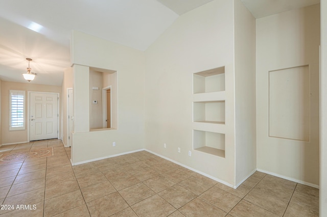 unfurnished room with baseboards, built in shelves, and light tile patterned flooring