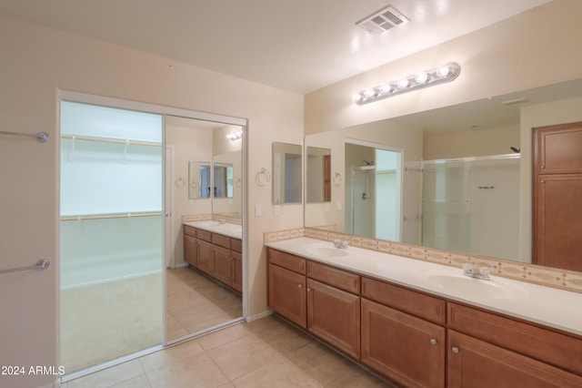 full bath featuring double vanity, visible vents, a stall shower, and a sink