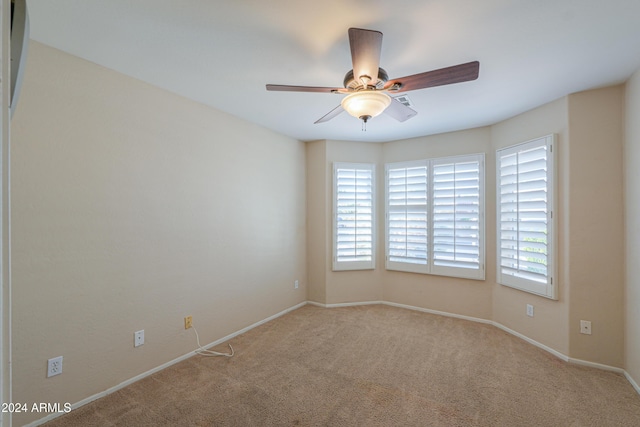 carpeted empty room featuring a ceiling fan and baseboards