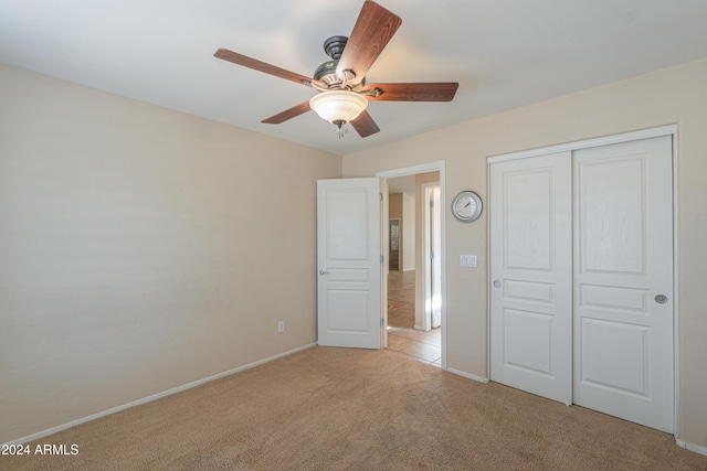 unfurnished bedroom featuring a closet, light colored carpet, baseboards, and ceiling fan