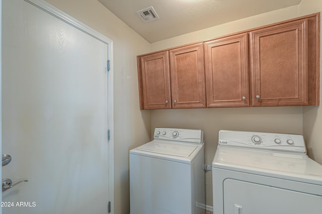 clothes washing area with cabinet space, visible vents, and washing machine and dryer