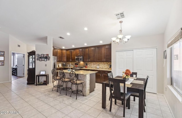 7457 W Crystal Rd, Glendale, AZ 85308 - kitchen featuring a notable chandelier, light tile patterned flooring, stainless steel microwave, dark brown cabinetry, and tasteful backsplash