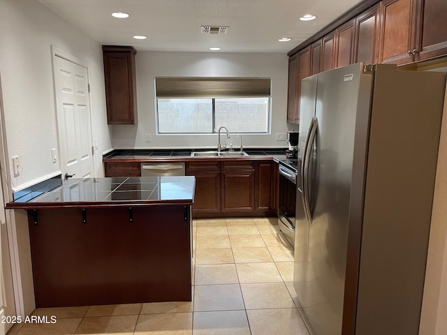 kitchen featuring sink, light tile patterned floors, a breakfast bar area, stainless steel appliances, and kitchen peninsula