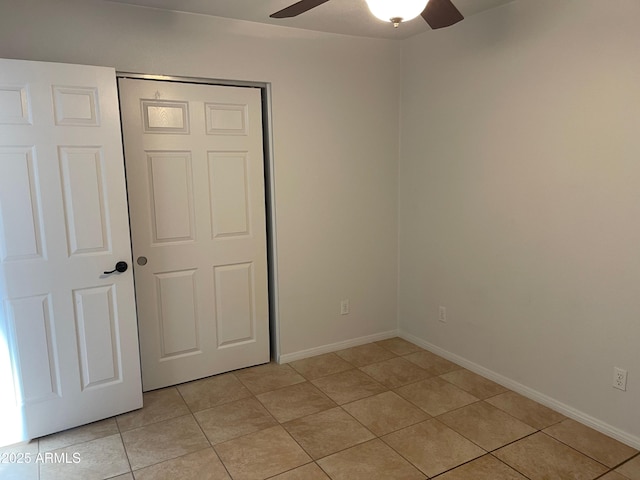 unfurnished bedroom with light tile patterned floors, ceiling fan, and a closet