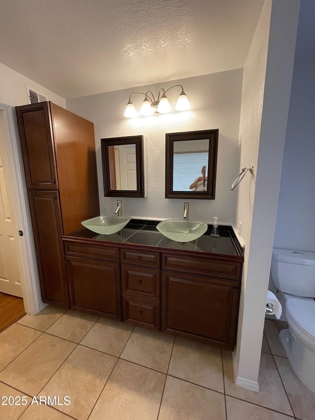 bathroom with vanity, toilet, tile patterned flooring, and a textured ceiling