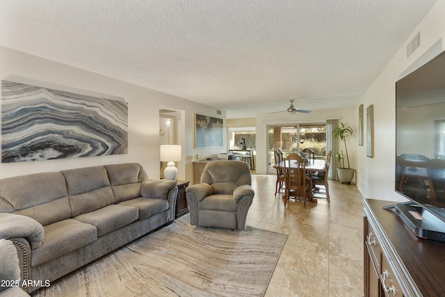 living room with light tile patterned flooring, ceiling fan, and a textured ceiling