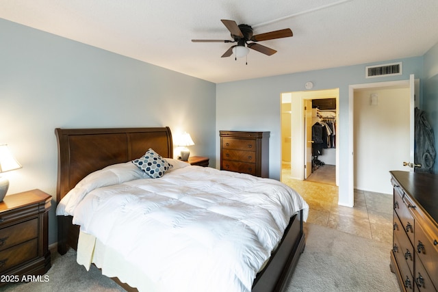 bedroom with a walk in closet, light carpet, ceiling fan, and a closet