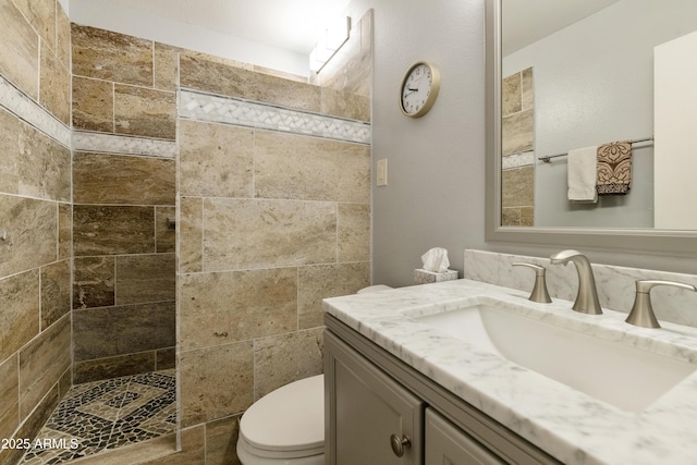 bathroom with vanity, toilet, and a tile shower