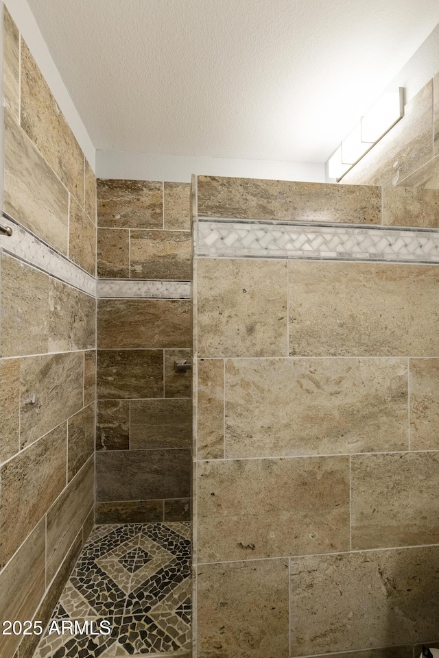 bathroom featuring tiled shower and a textured ceiling