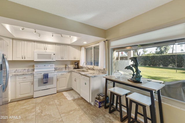 kitchen featuring sink, white cabinets, light tile patterned floors, light stone countertops, and white appliances