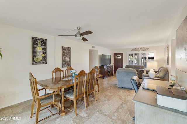 dining area featuring ceiling fan and a textured ceiling