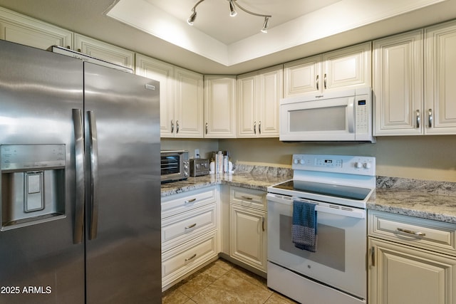 kitchen featuring white appliances, a tray ceiling, light stone countertops, and light tile patterned floors