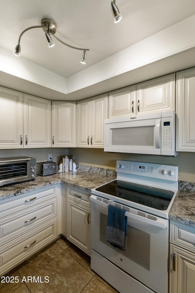 kitchen with white cabinetry, white appliances, and dark tile patterned floors