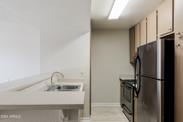 kitchen featuring black electric range oven, sink, white cabinetry, kitchen peninsula, and stainless steel refrigerator