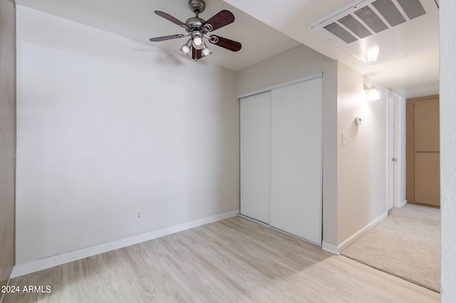 unfurnished bedroom with ceiling fan, light hardwood / wood-style flooring, and a closet