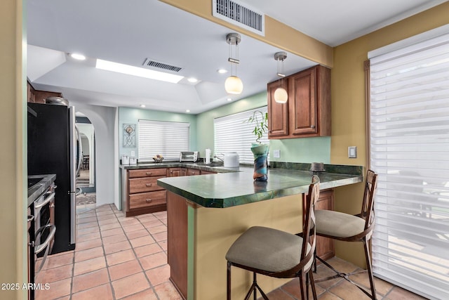 9012 S 47th Pl, Phoenix, AZ 85044 - kitchen featuring brown cabinets, a peninsula, range with two ovens, and visible vents