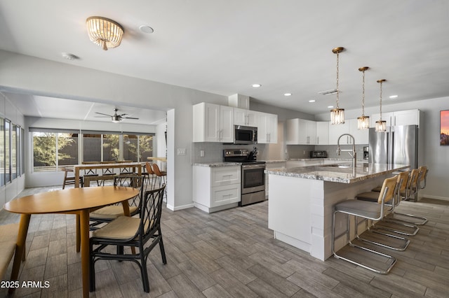 4904 E Tierra Buena Ln, Scottsdale, AZ 85254 - kitchen featuring a sink, ceiling fan, white cabinetry, stainless steel appliances, and decorative backsplash
