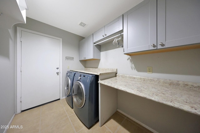 laundry area with cabinets, washing machine and clothes dryer, and light tile patterned floors