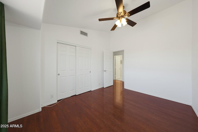 unfurnished bedroom with ceiling fan, a closet, and dark wood-type flooring