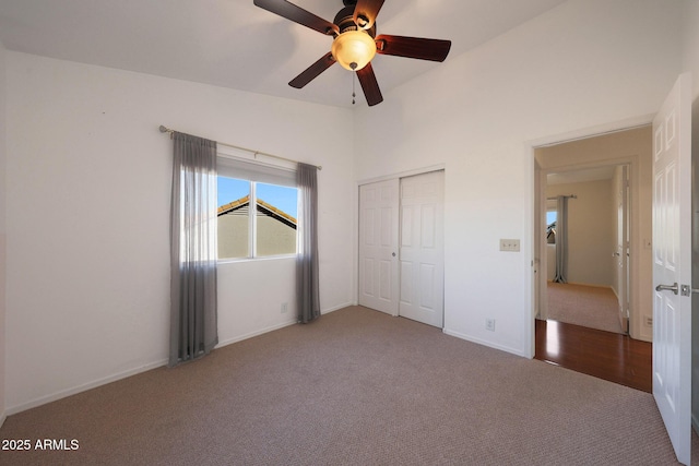 unfurnished bedroom featuring ceiling fan, carpet flooring, a closet, and lofted ceiling