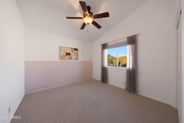 empty room featuring ceiling fan, vaulted ceiling, and carpet floors