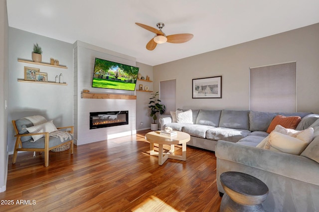 living room with ceiling fan, a large fireplace, and hardwood / wood-style flooring