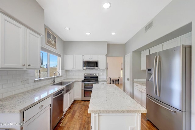 kitchen with white cabinets, a center island, appliances with stainless steel finishes, and sink