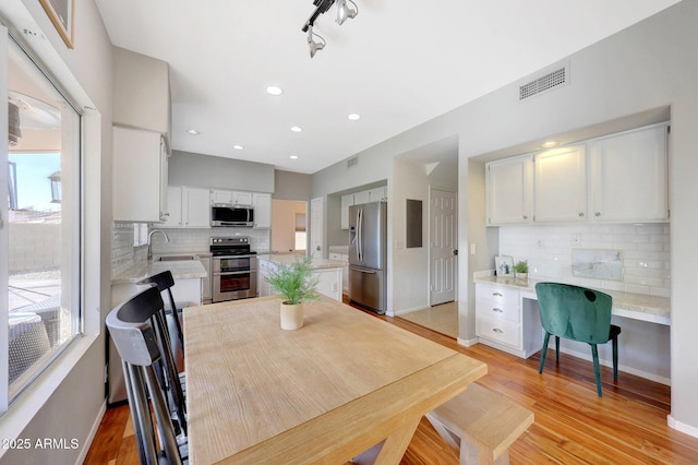 dining room with sink, light hardwood / wood-style floors, built in desk, and plenty of natural light