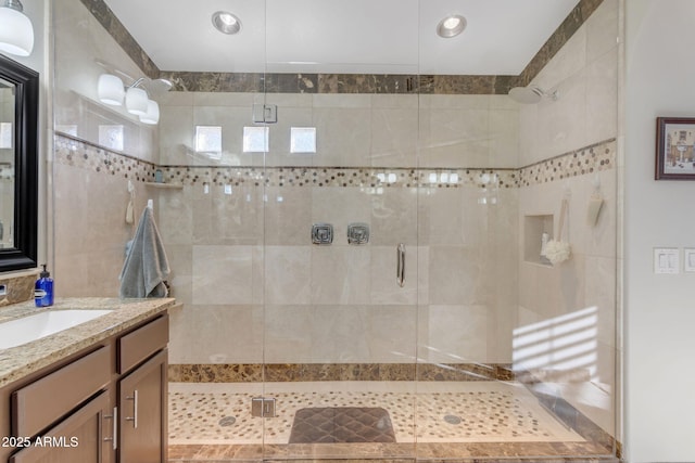 bathroom featuring a shower with door and vanity