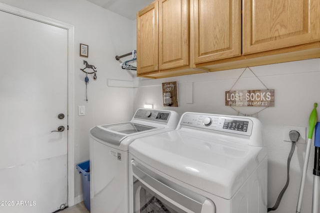 clothes washing area featuring cabinets and washer and dryer