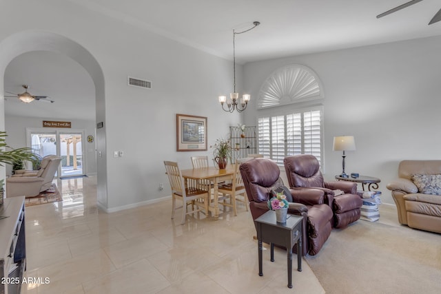 tiled living room featuring ceiling fan with notable chandelier and a high ceiling