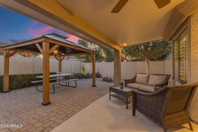 patio terrace at dusk with a gazebo, ceiling fan, and outdoor lounge area