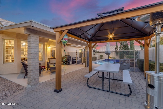 patio terrace at dusk featuring a fenced in pool and a gazebo