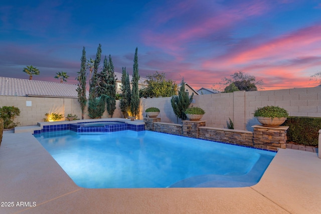 pool at dusk featuring an in ground hot tub