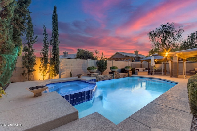 pool at dusk with an in ground hot tub and a patio area