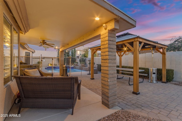 patio terrace at dusk with a fenced in pool, a gazebo, and ceiling fan