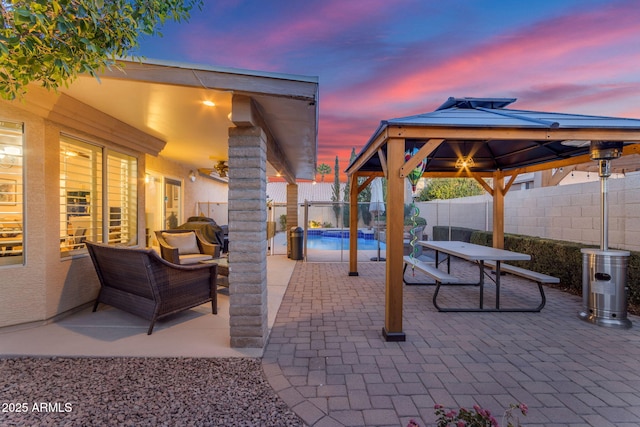 patio terrace at dusk featuring a gazebo, an outdoor living space, and a fenced in pool