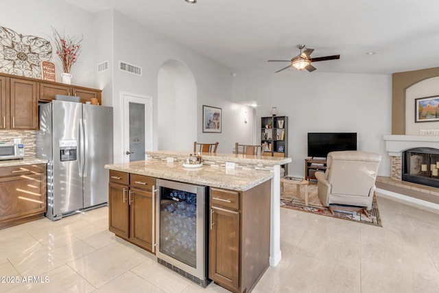 kitchen featuring stainless steel refrigerator with ice dispenser, a kitchen island, beverage cooler, and backsplash